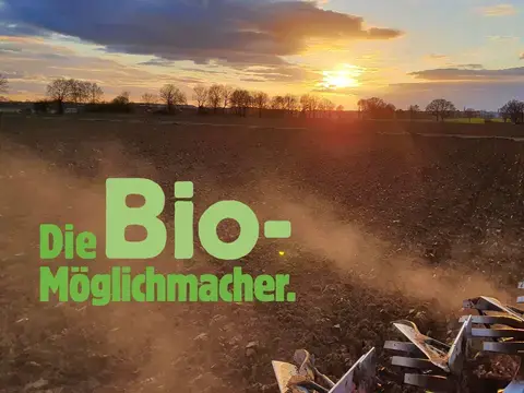 Stimmungsbild "Die Bio-Möglichmacher": Landmaschine pflügt ein Feld im Sonnenuntergang