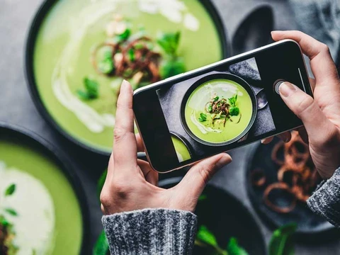 Es wird mit einem Handy ein Foto von einer Suppe für Social Media gemacht.