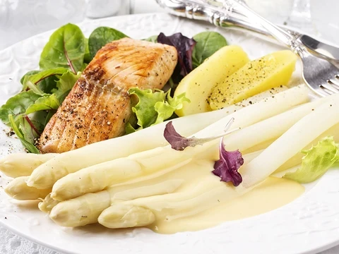 Weißer Stangenspargel mit Hollandaise, Salzkartoffeln und Lachsfilet auf einem Salatbett