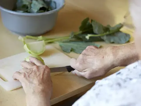 Eine Seniorin schnippelt Kohlrabi